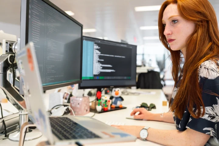 Woman working at a computer with two external screens